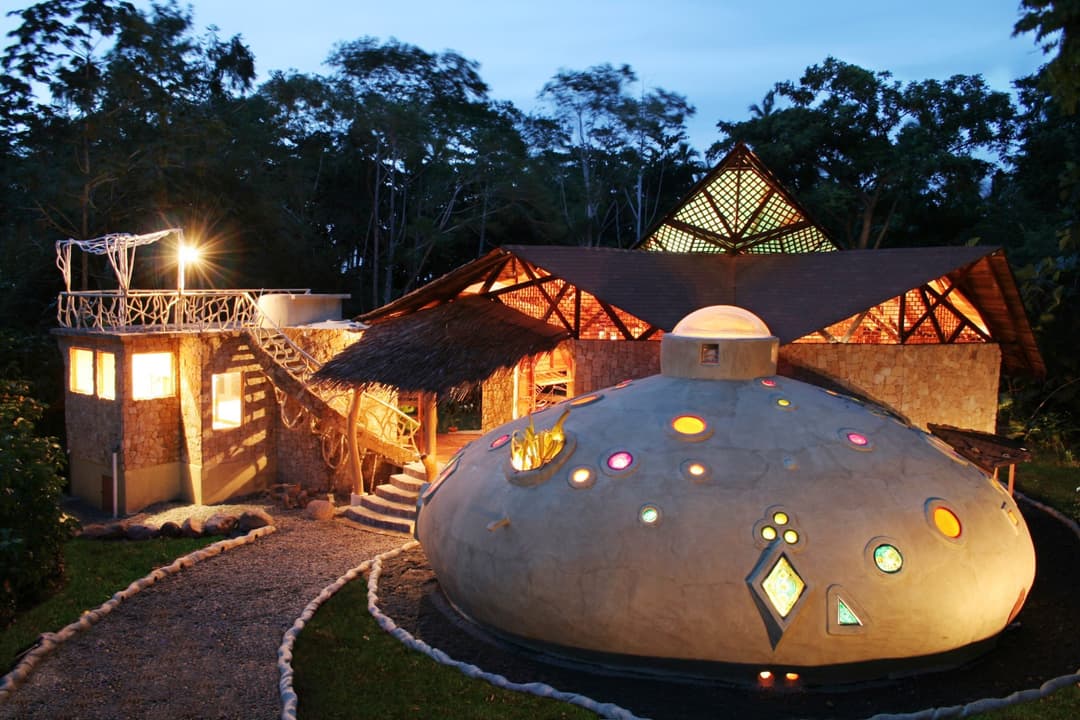 Evening view of the Beach Suite — mosaic dome and main house lit golden from within, rooftop terrace silhouetted