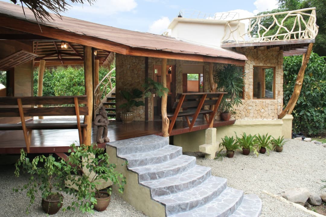 Side entry of the A/C wing — covered hardwood deck, stone steps, rooftop terrace balcony above