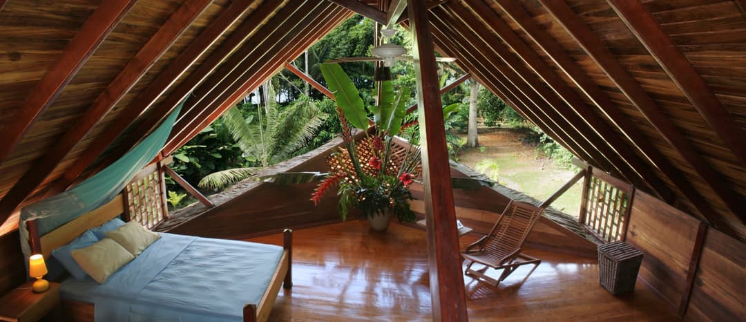 A-frame attic loft with a queen day-bed beneath the gables, open lattice gable looking into the canopy